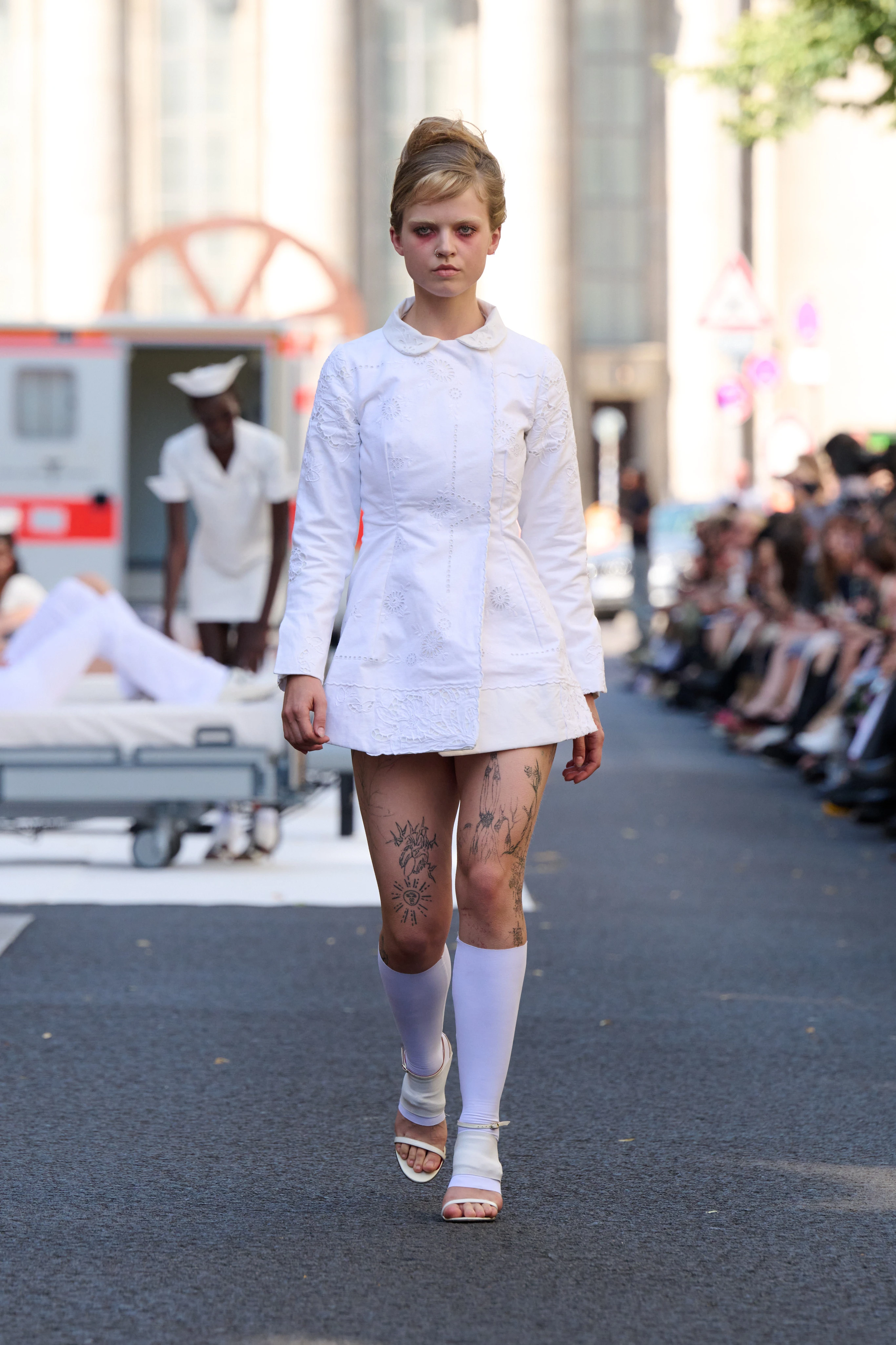 White dress from Clara Colette Miramon SS26 collection at Berlin Fashion Week worn by a model. Styled with knee-high socks.