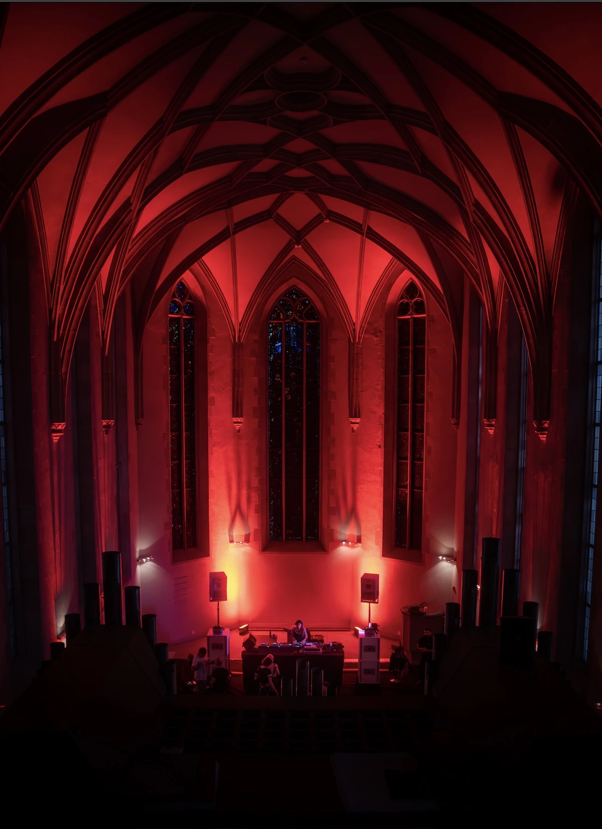A DJ performing in a red-lit vaulted church interior during Zurich Music Week, with the audience gathered below.